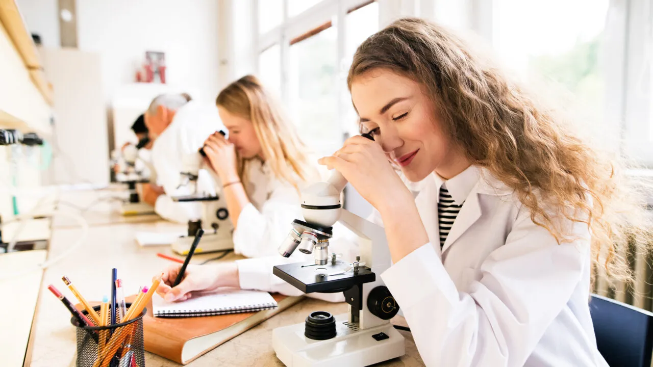 High school Students With Microscopes in Laboratory.